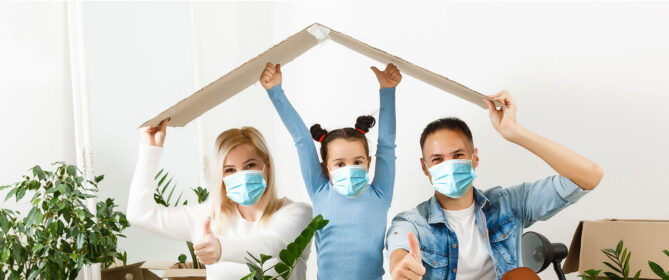 family with mask carrying cardboard house roof